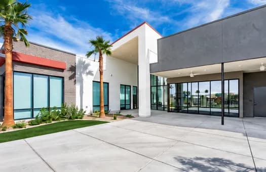 Exterior of Gholson Landing's clubhouse building, a modern structure with large glass storefronts and two palm trees out front