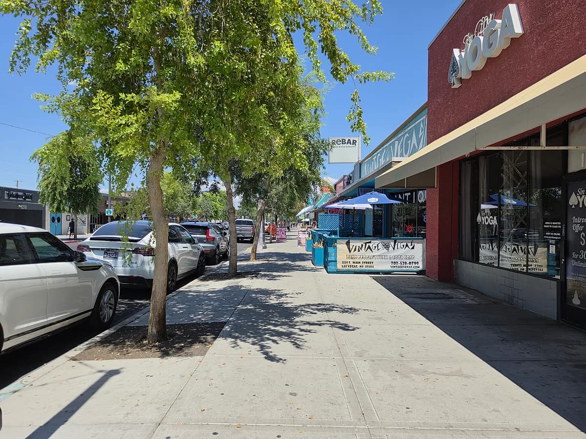 A tree-lined sidewalk along Main Street in the Las Vegas Arts District, with shaded storefronts and street trees running down the block.