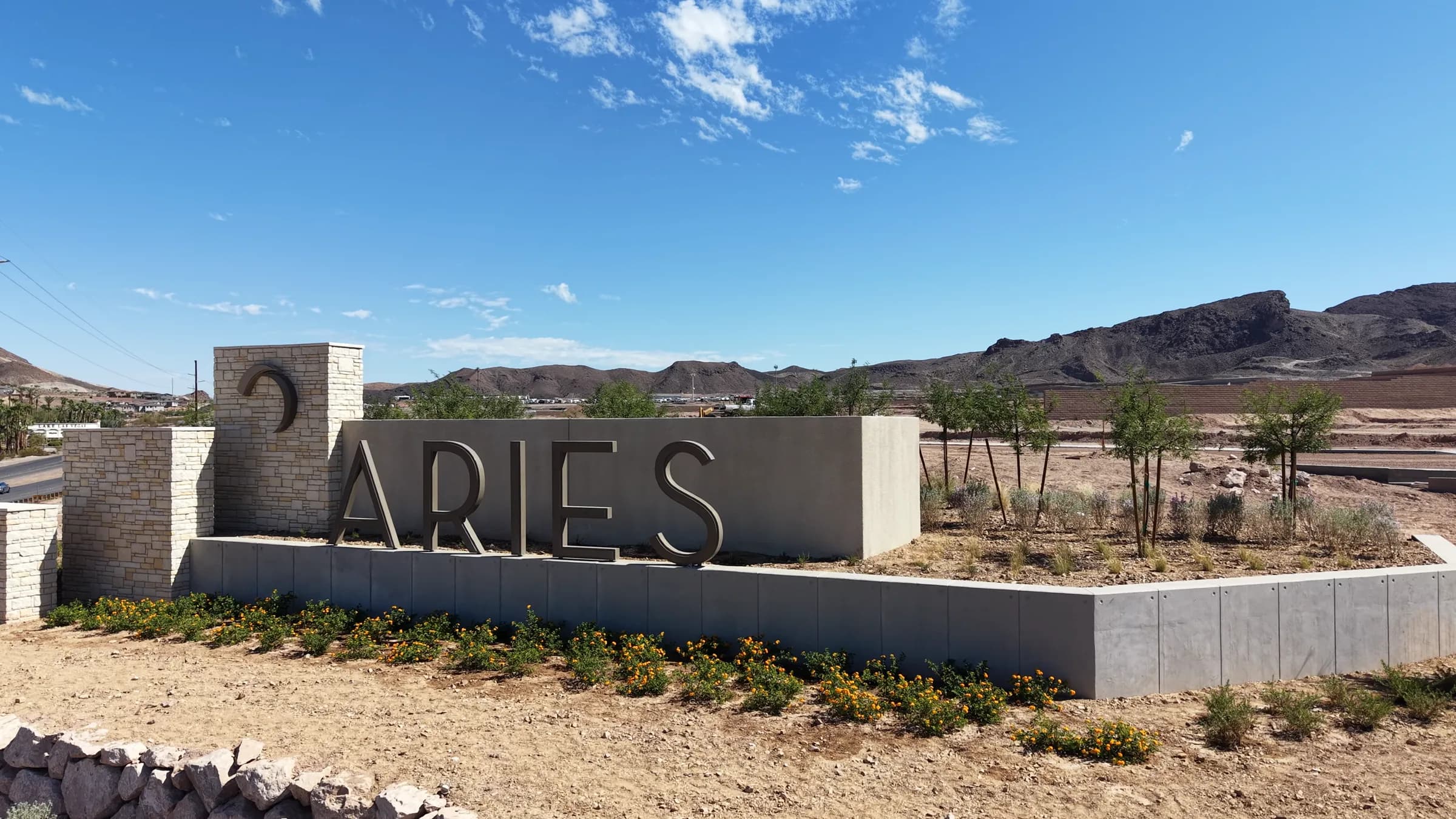 Photo: Mikey Del Rosario The Aries monument sign at the community entrance in east Henderson, with new landscaping in front and desert mountains behind it under a blue sky.