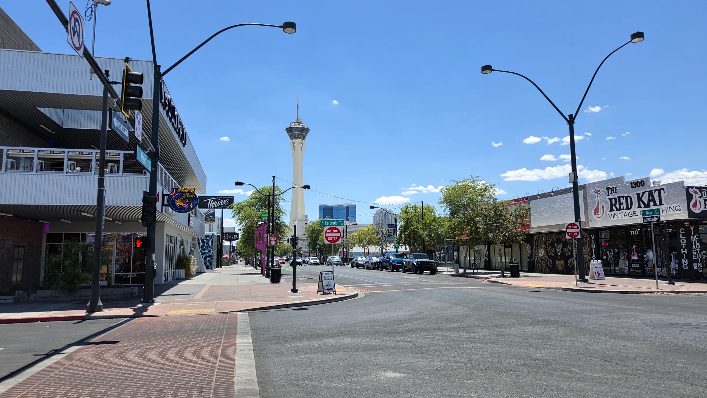 Main Street in the Las Vegas Arts District at midday, looking north toward the Stratosphere tower, with the mid-century Colorado building on the left and The Red Kat vintage store on the right.