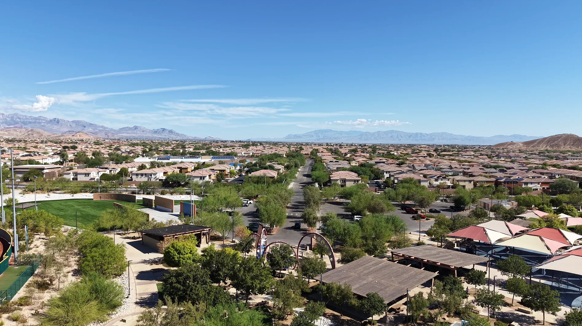 Aerial drone view of a park in Mountain's Edge, a master-planned Southwest Las Vegas community, with the valley and mountains beyond.